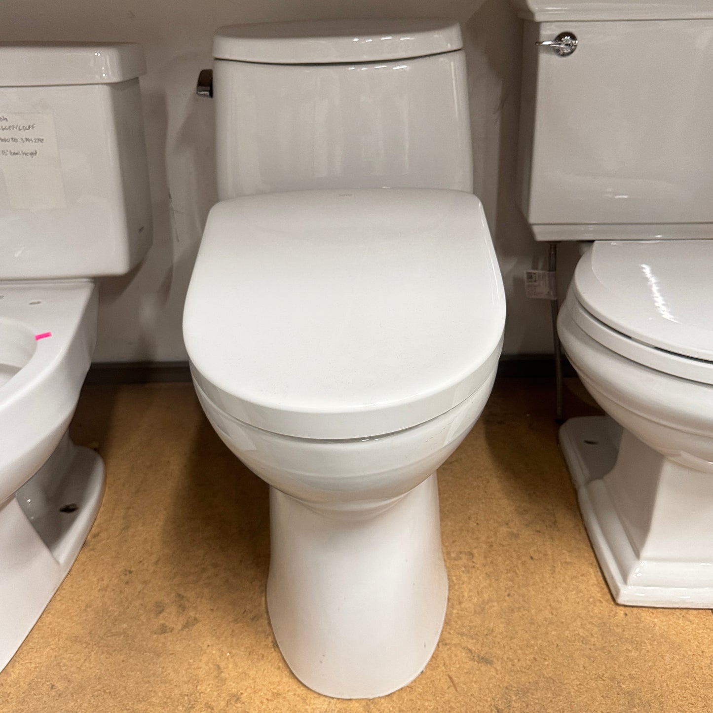 Close-up of a white toilet with a wooden floor and wall in the background